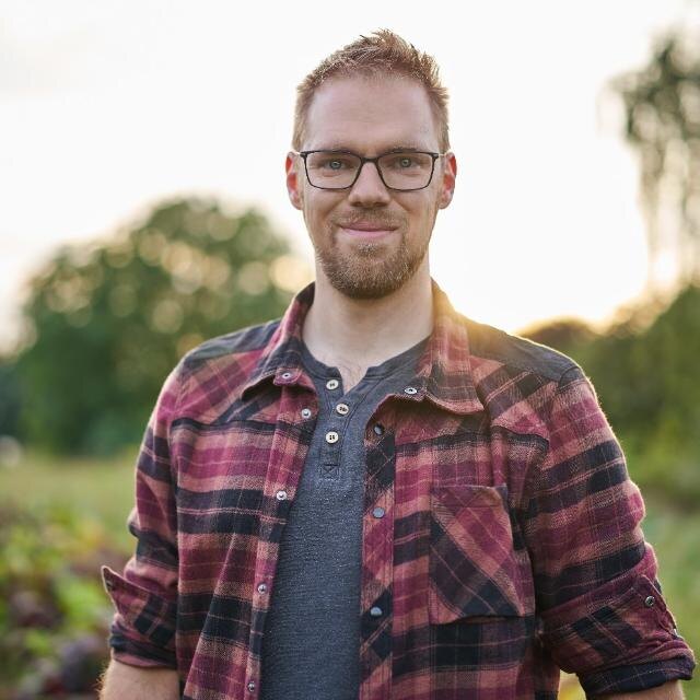 Stephan Noack mit Brille und kariertem Hemd im Freien
