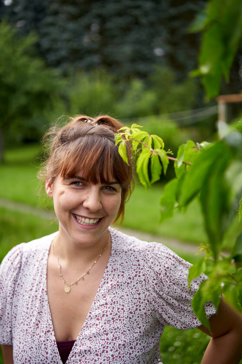 Eine Frau lächelt zwischen grünen Blättern in die Kamera
