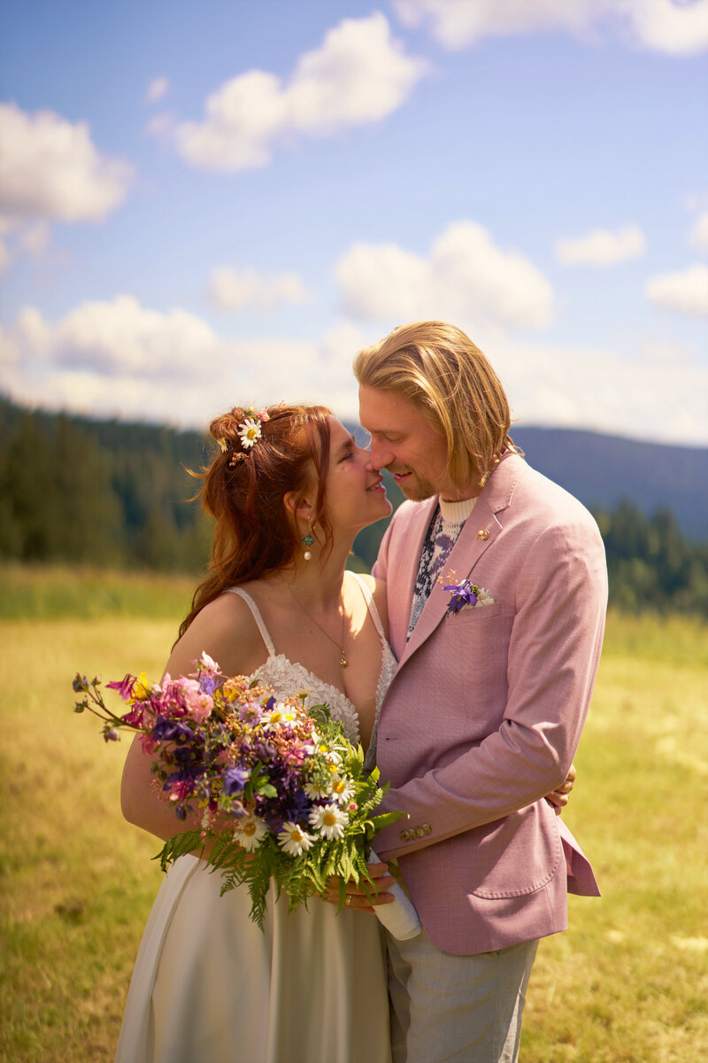 Ein Hochzeitspaar steht einander lächelnd zugewandt auf einer Wiese
